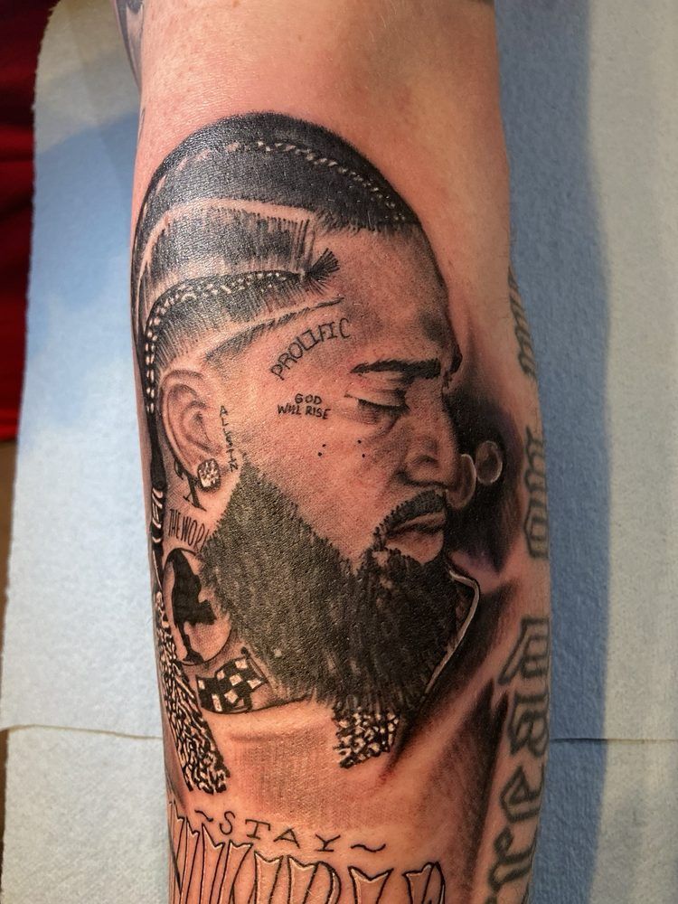 A man has a tattoo of a man with a beard on his arm