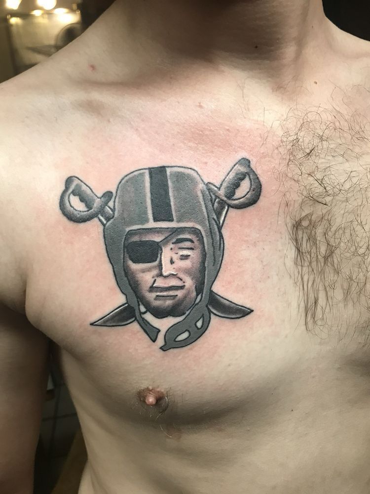 A man has a raiders tattoo on his chest.