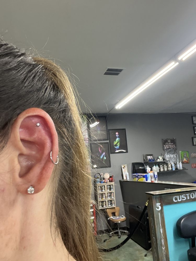 A close up of a woman 's ear with a piercing and earrings.