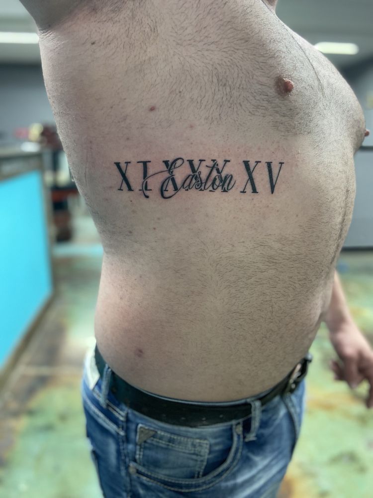 A man has a tattoo of roman numerals on his side