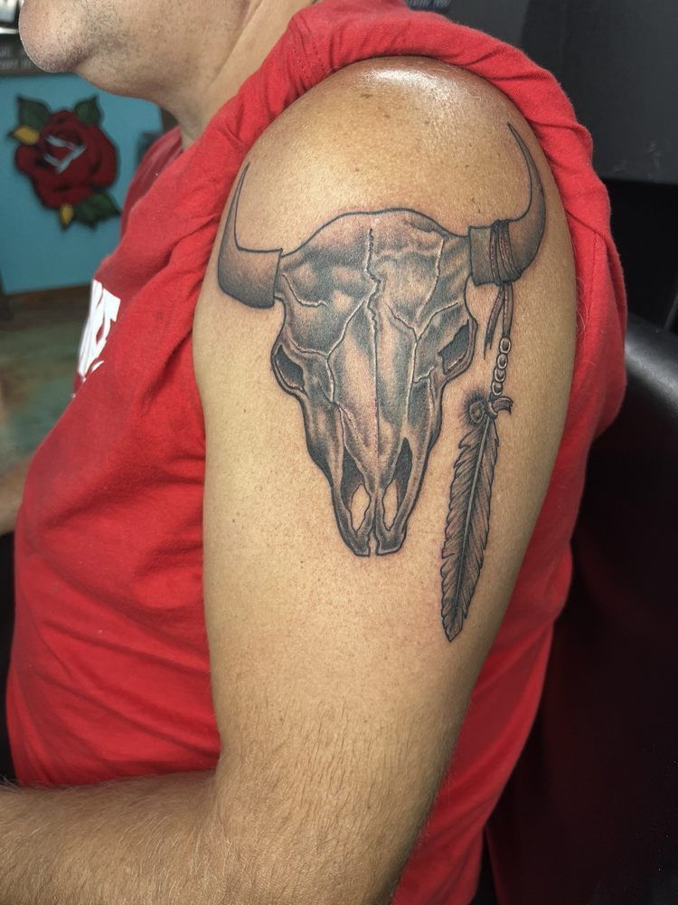 A man has a bull skull tattoo on his arm