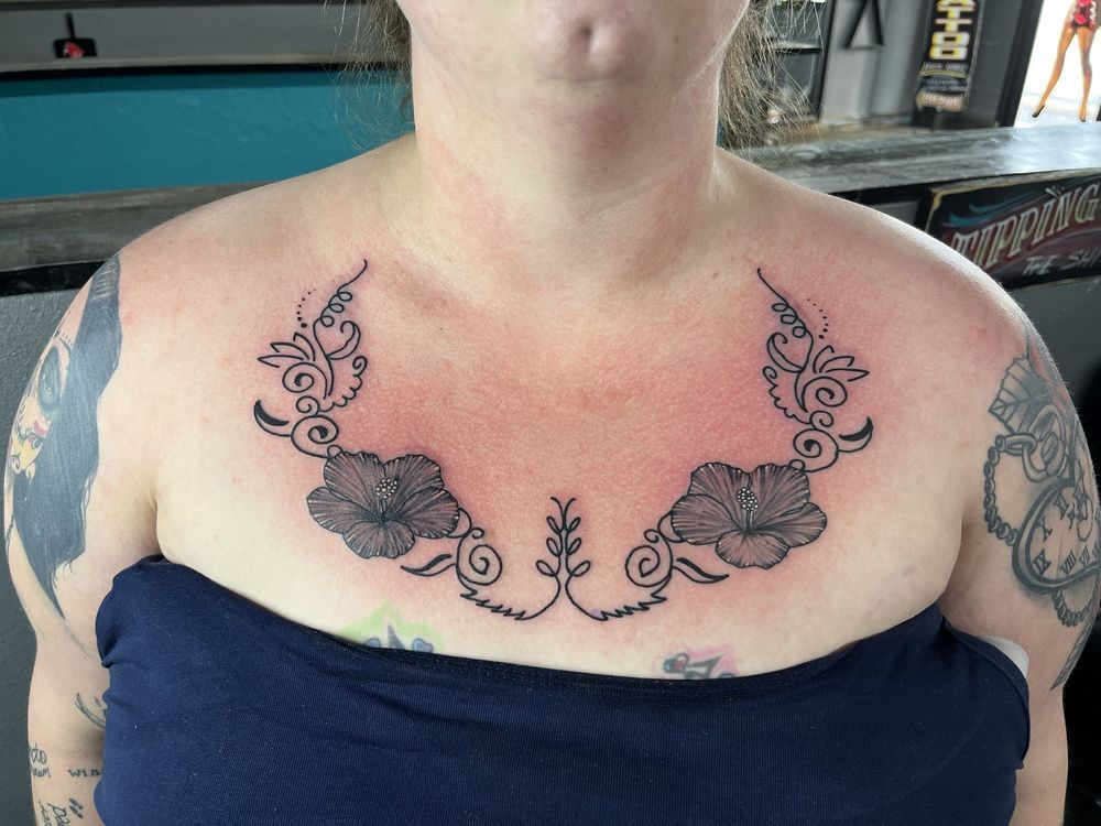 A woman has a tattoo of flowers on her chest