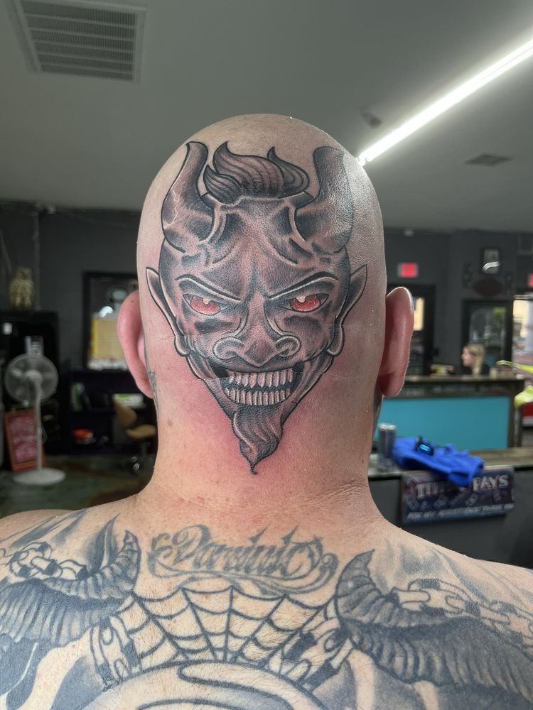 A man has a tattoo of a devil on his head