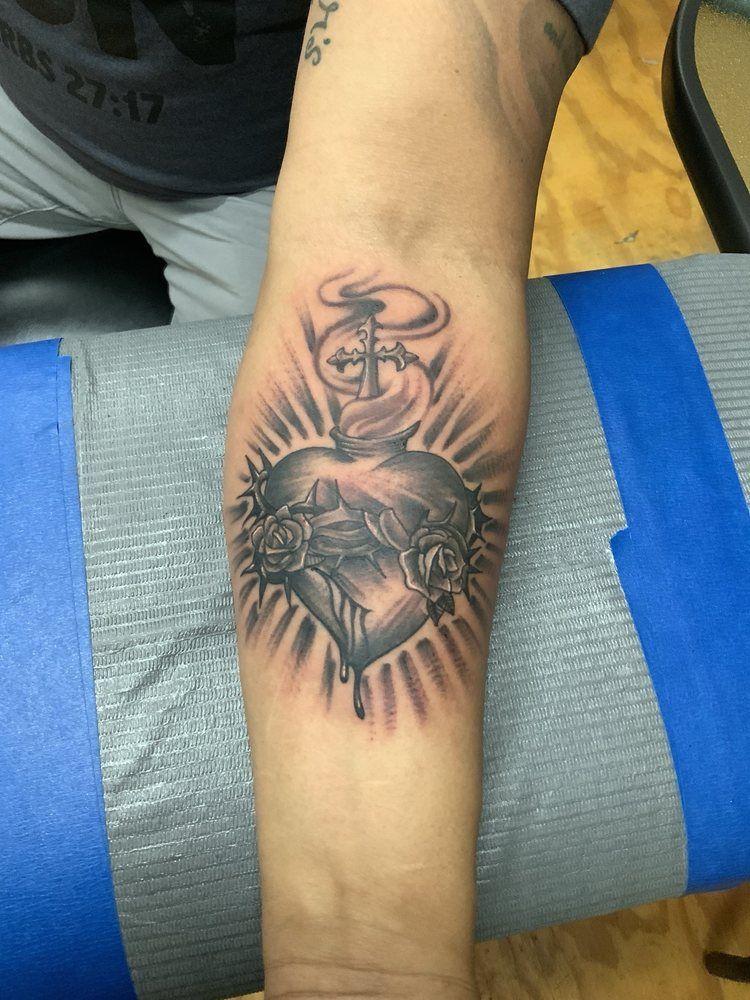 A tattoo of a heart with a cross on it