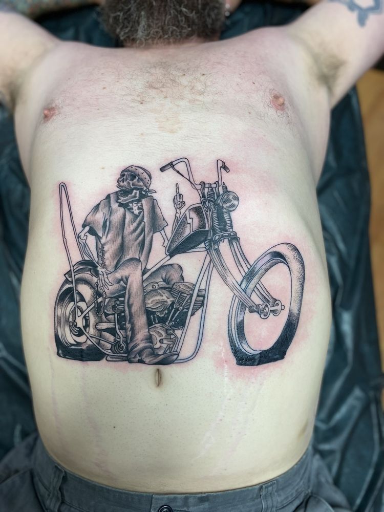 A man has a tattoo of a man sitting on a motorcycle