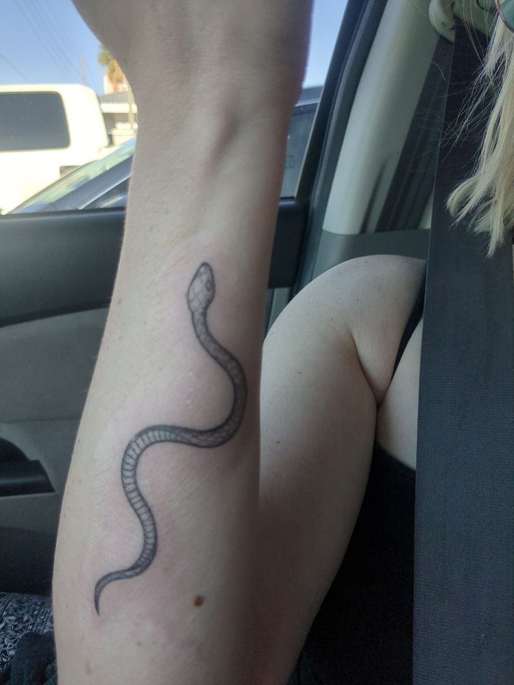 A woman has a tattoo of a snake on her wrist