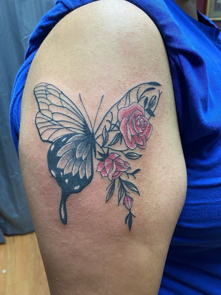 A woman has a tattoo of a butterfly and roses on her shoulder.