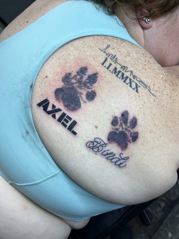 A woman has two paw prints and the name axel on her back.