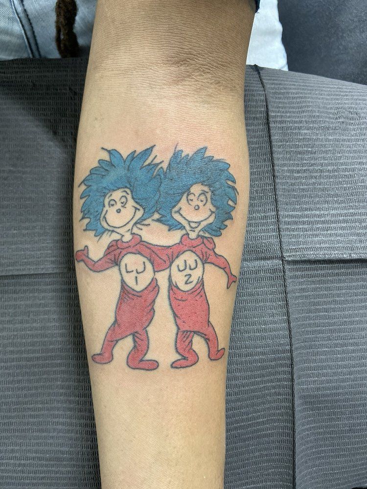 A person has a tattoo of two thing 1 and thing 2 on their forearm.