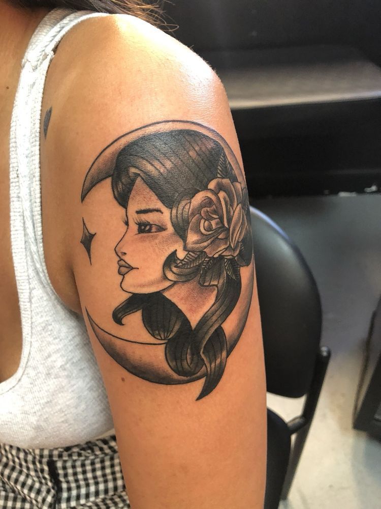 A woman has a tattoo of a woman 's face on a crescent moon
