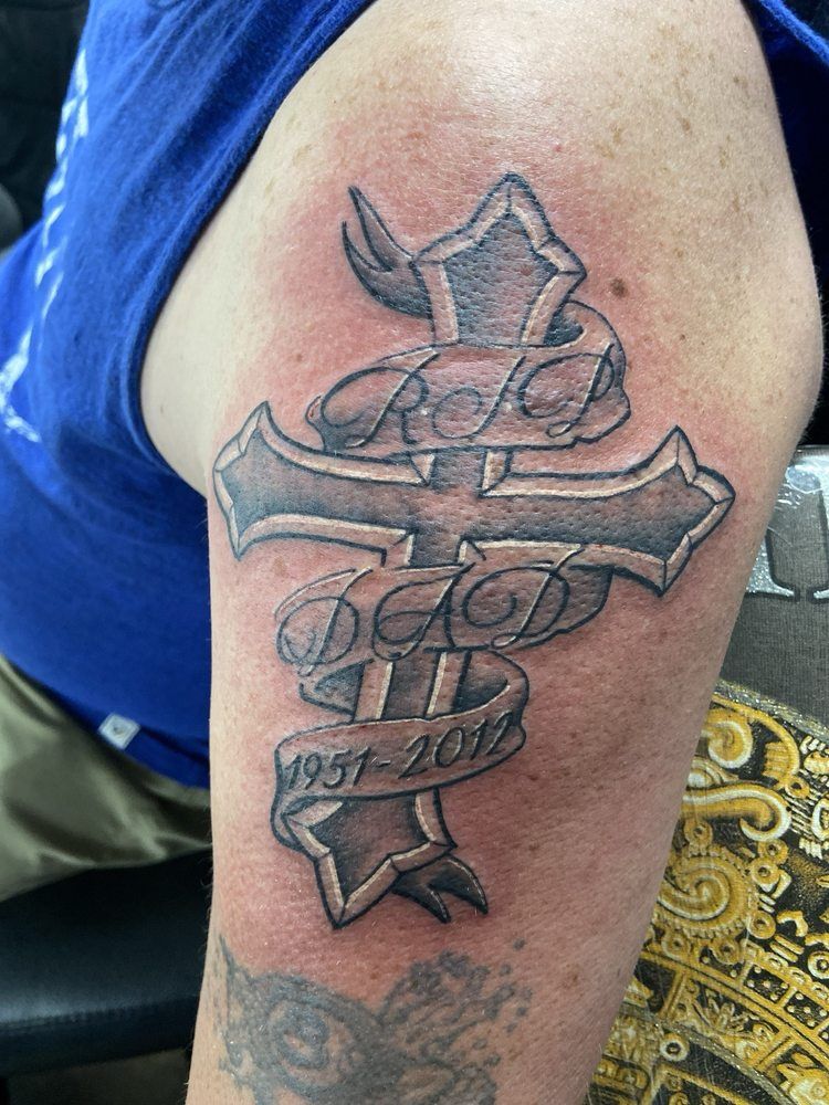 A man has a tattoo of a cross on his arm.