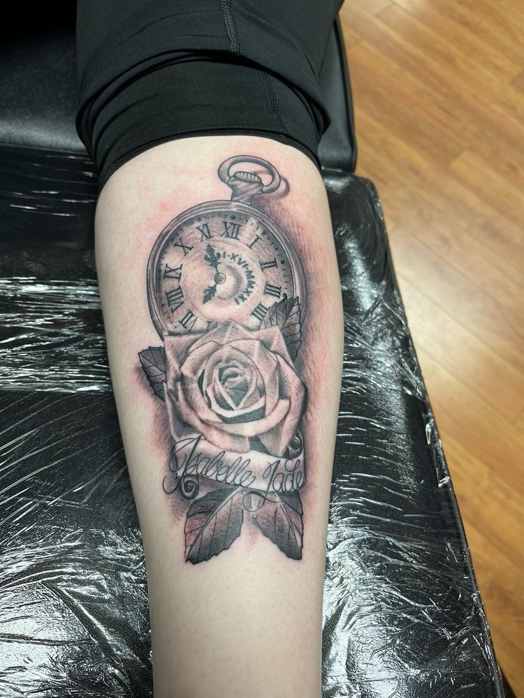 A person has a tattoo of a pocket watch and roses on their leg