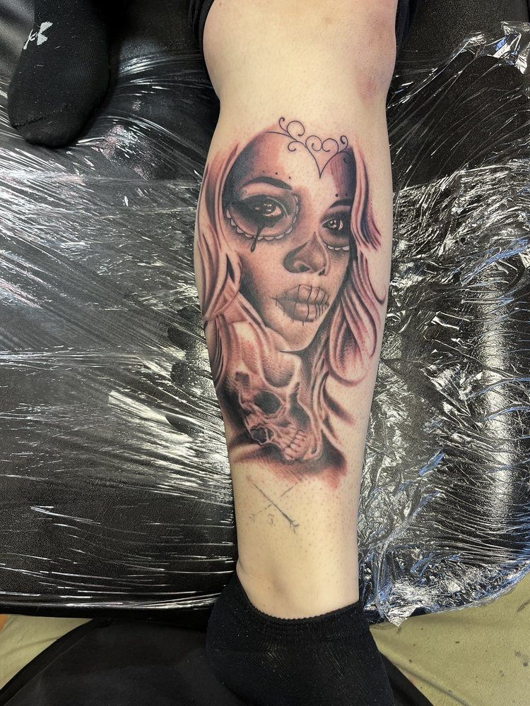 A tattoo of a woman with a skull on her leg