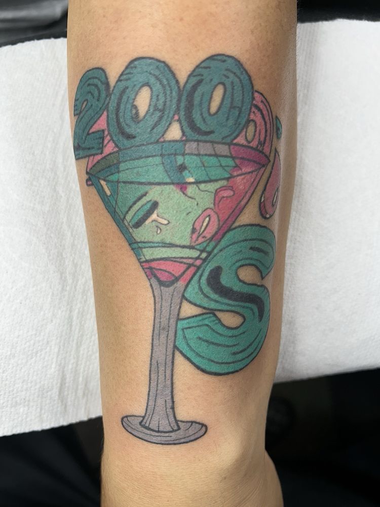 A tattoo of a martini glass with a face in it