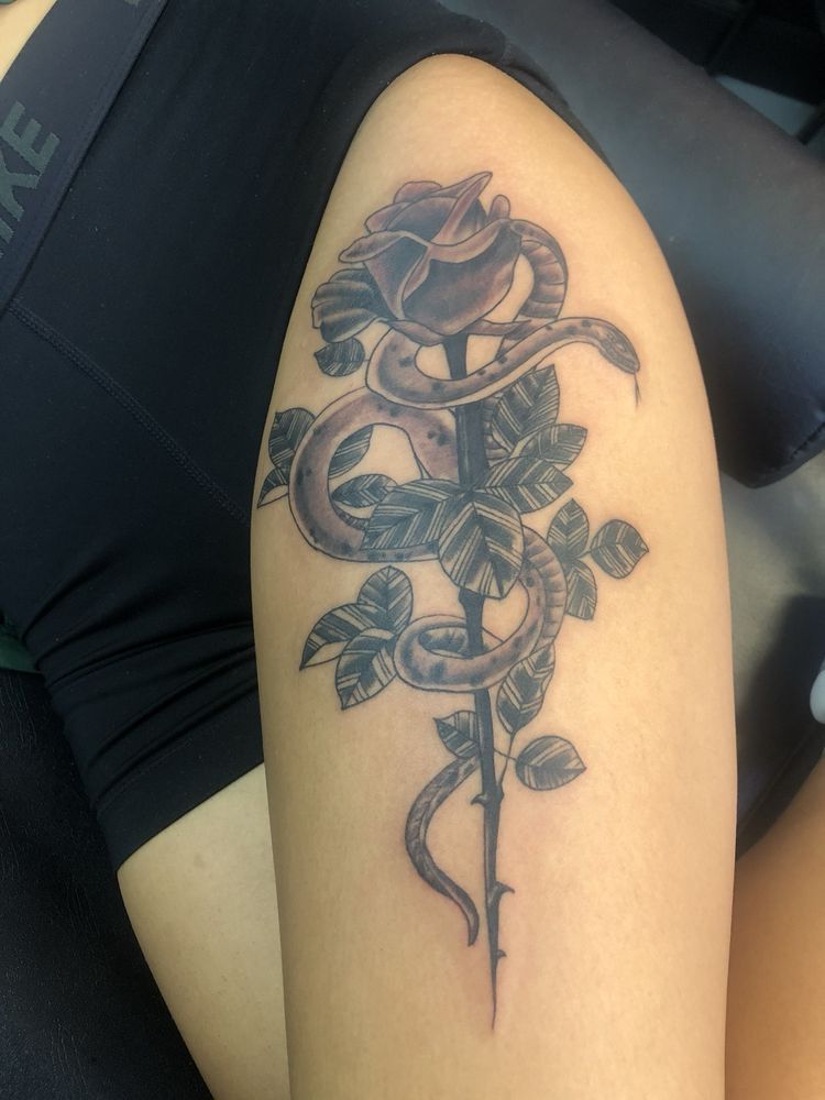 A woman has a tattoo of a rose with a snake around it