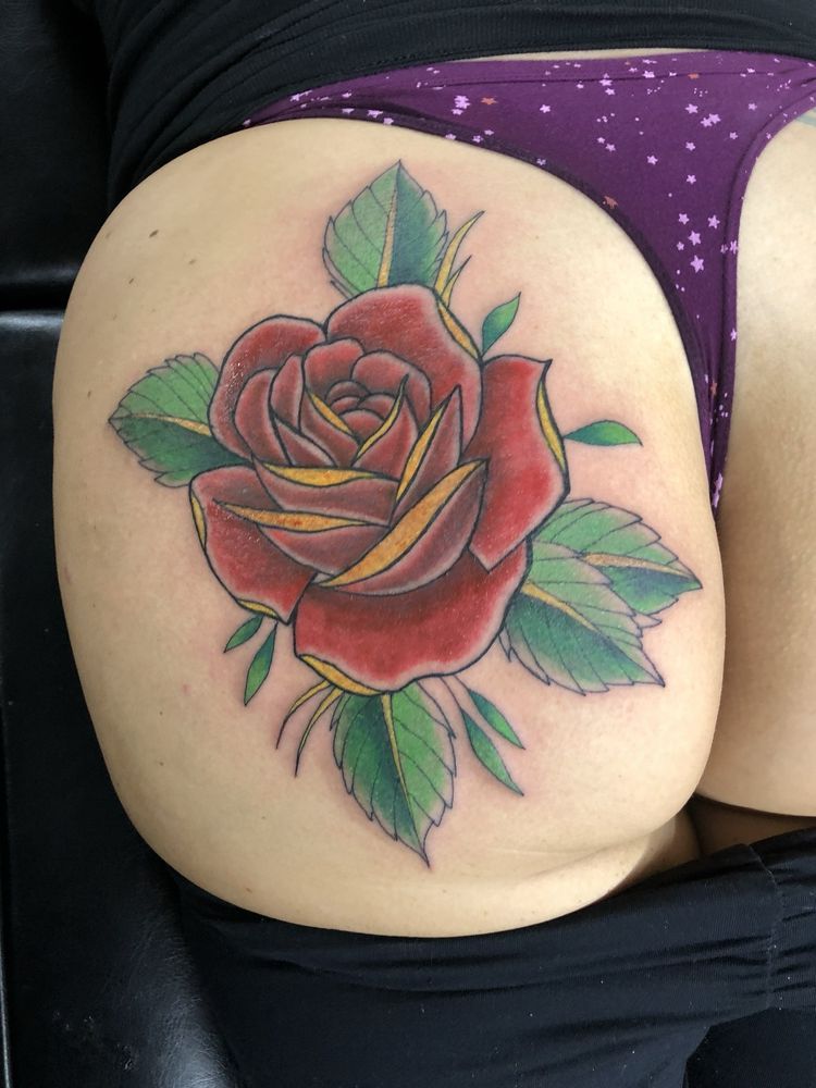 A woman has a tattoo of a red rose on her thigh