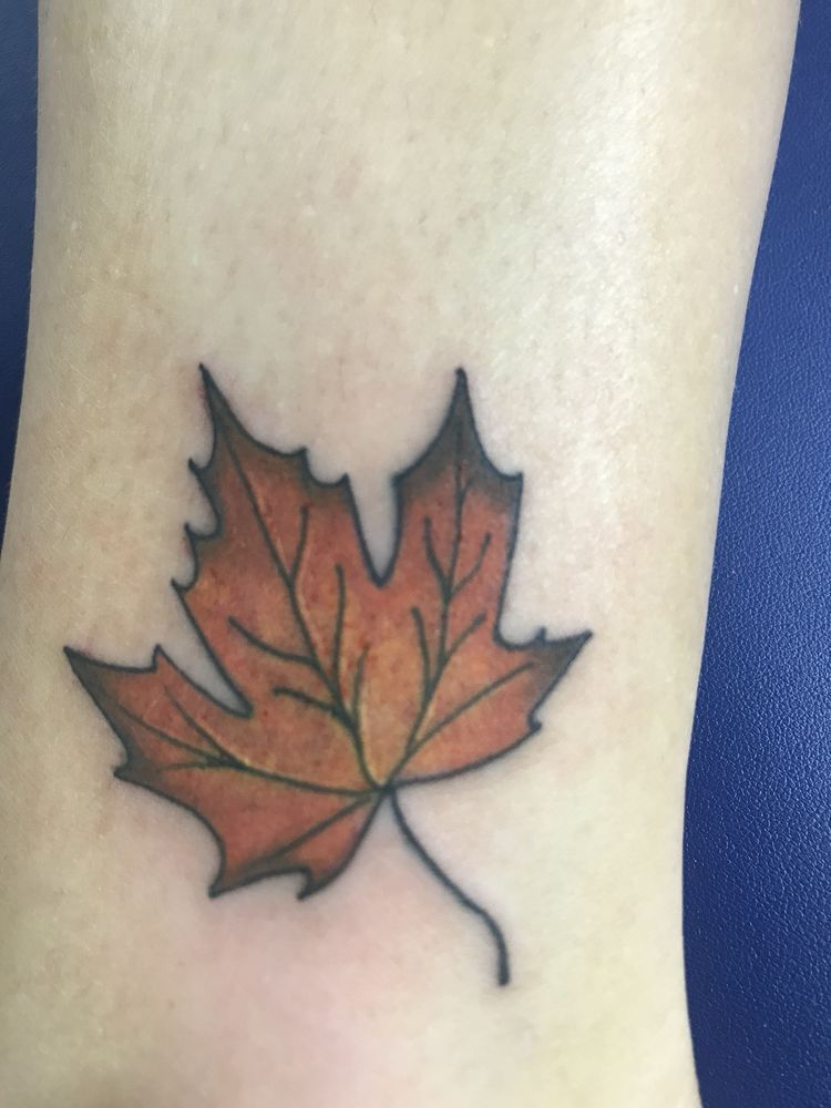 A person has a tattoo of a maple leaf on their ankle