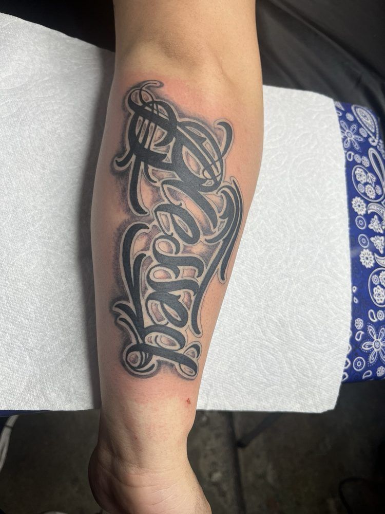 A person has a tattoo of the word believe on their arm.