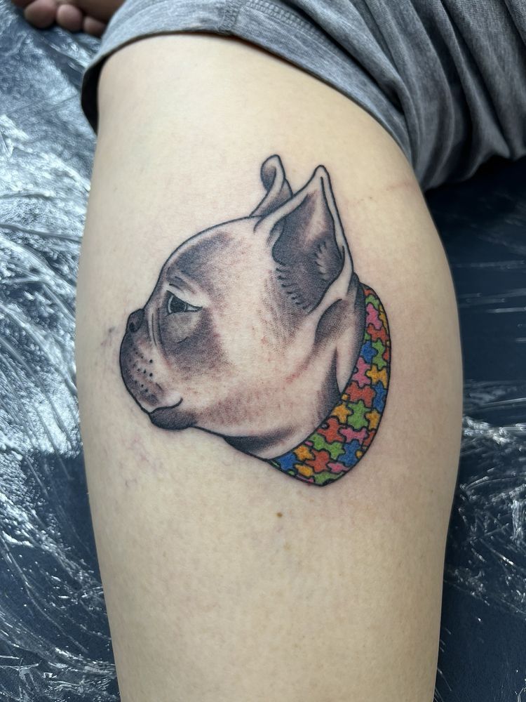 A person has a tattoo of a dog on their leg