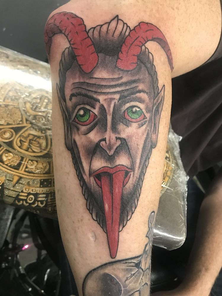 A person has a tattoo of a devil with horns on their arm.