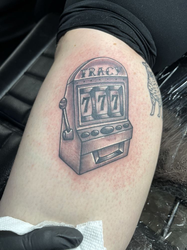 A person has a tattoo of a slot machine on their leg
