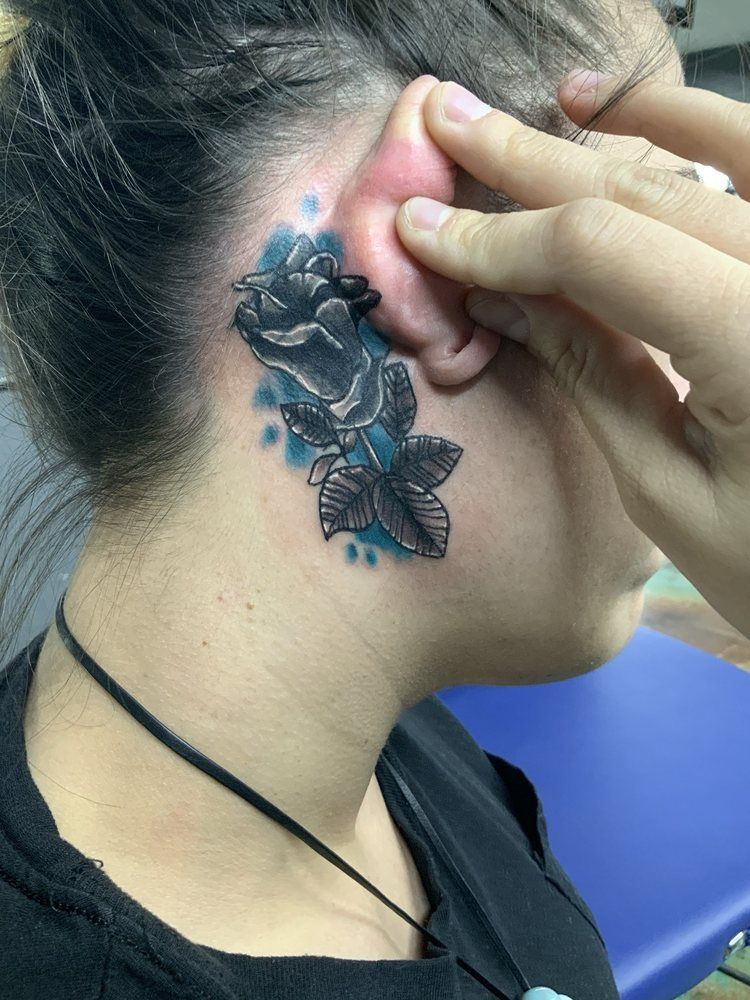 A woman has a tattoo of roses and butterflies behind her ear