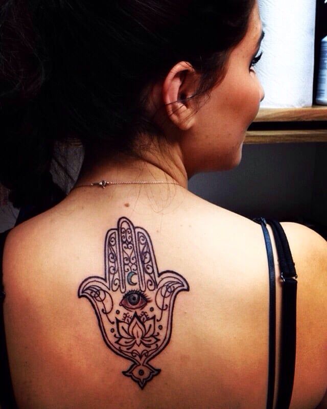 A woman has a hamsa tattoo on her back