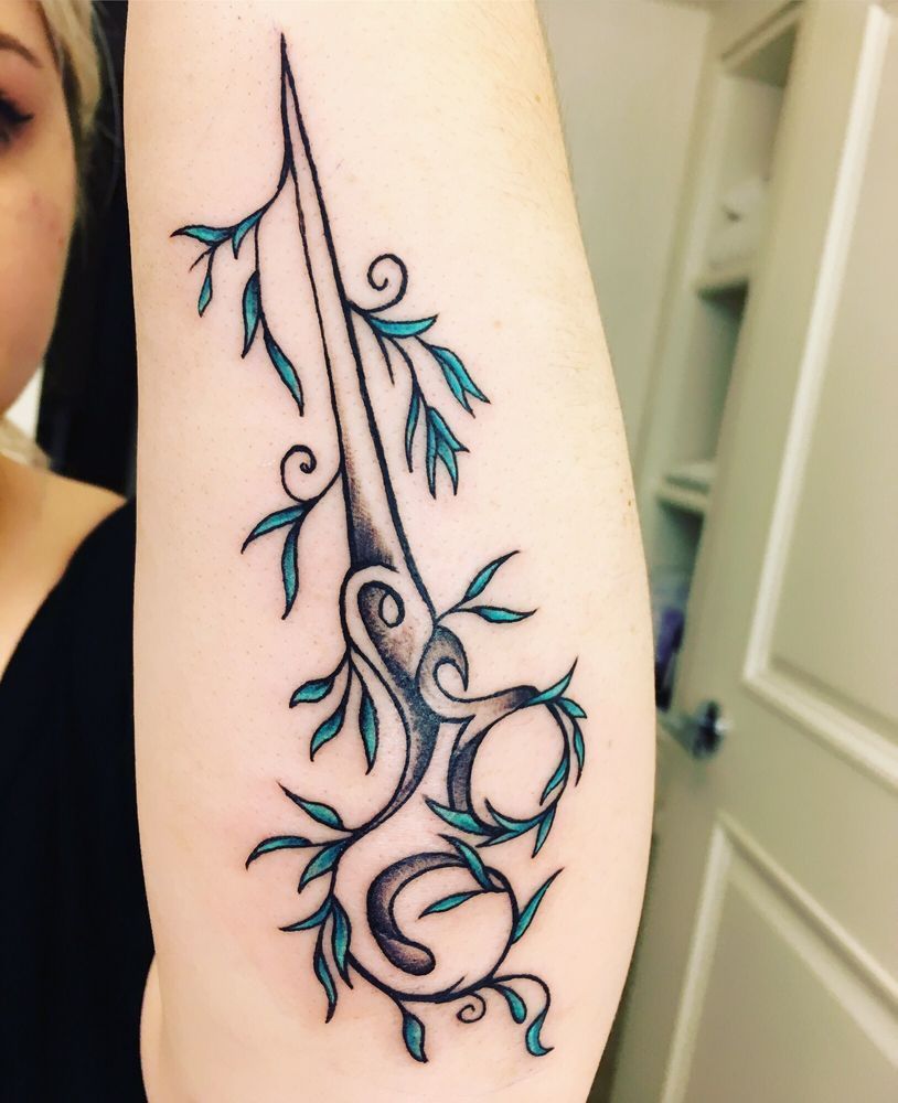 A woman has a tattoo of a pair of scissors on her arm