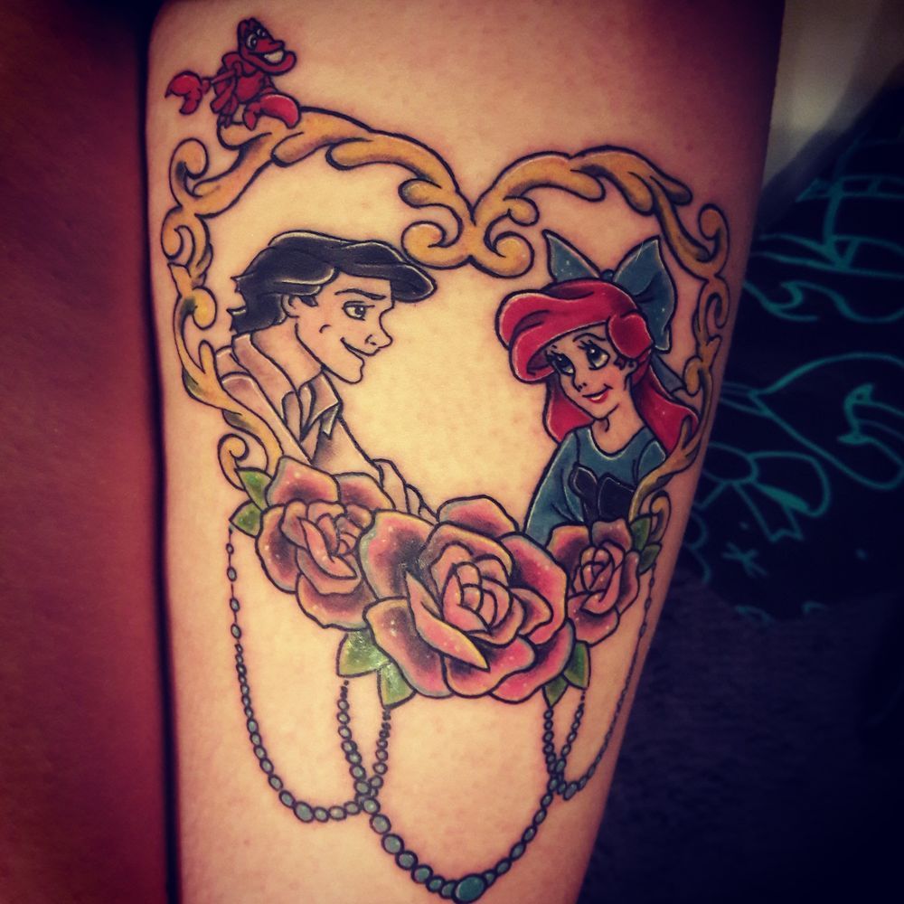 A tattoo of a man and woman in a heart surrounded by roses