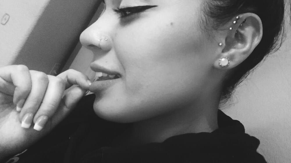 A black and white photo of a woman with a piercing in her ear.