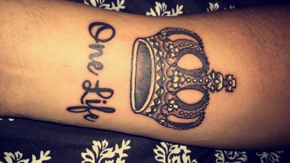 A woman has a tattoo of a crown and the words one life