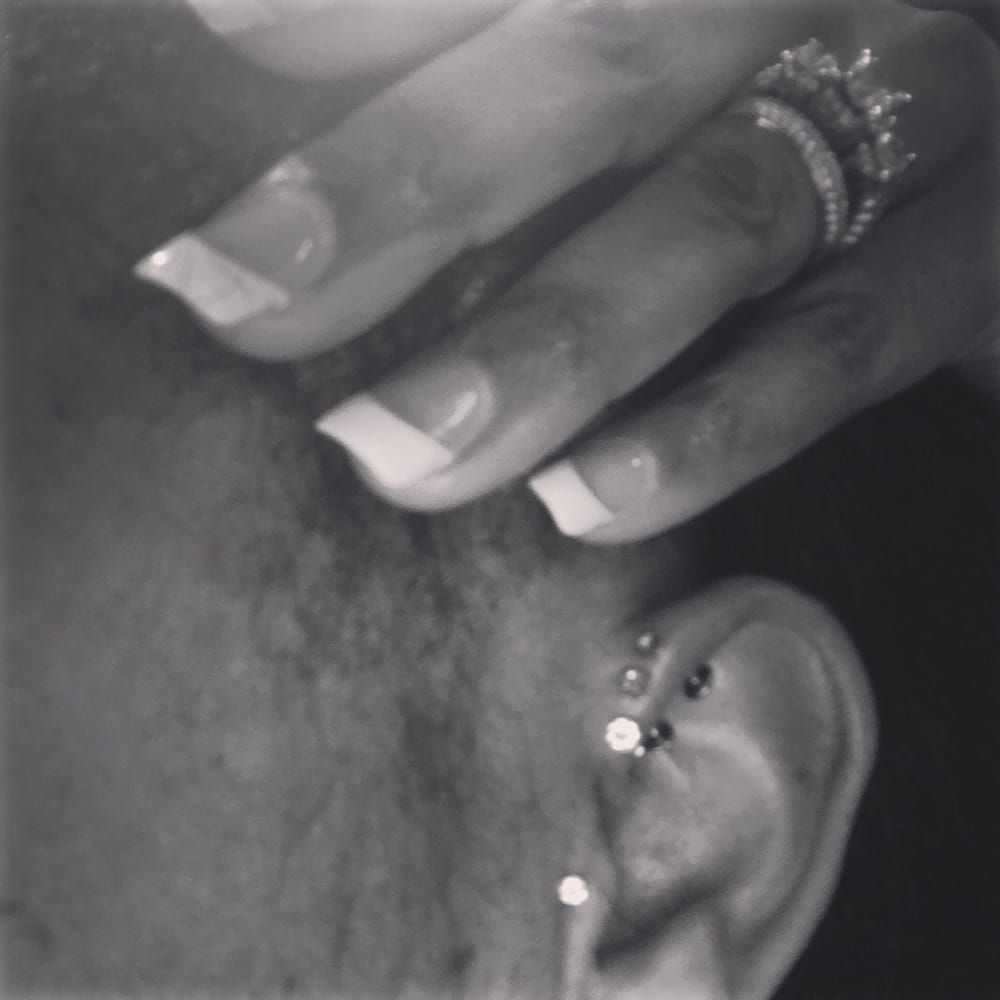 A black and white photo of a woman 's ear with a ring on her finger