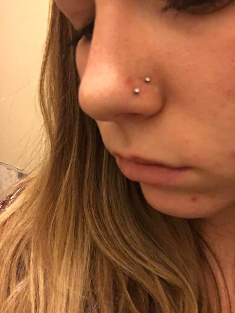 A close up of a woman 's nose with two piercings.
