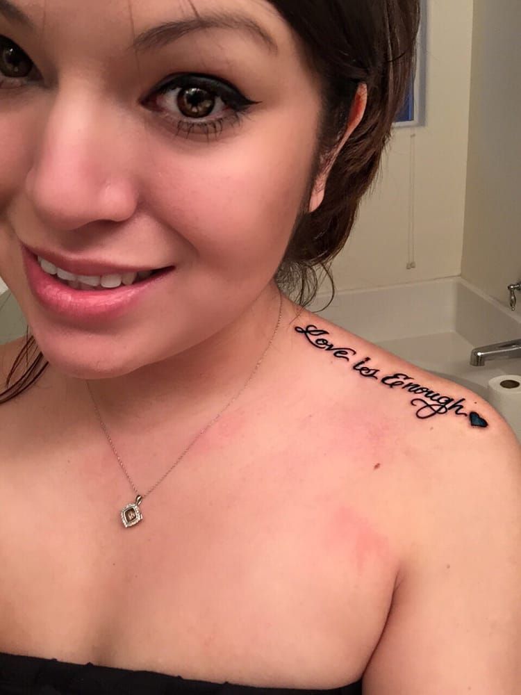 A woman has a tattoo on her shoulder that says `` love is enough ''.
