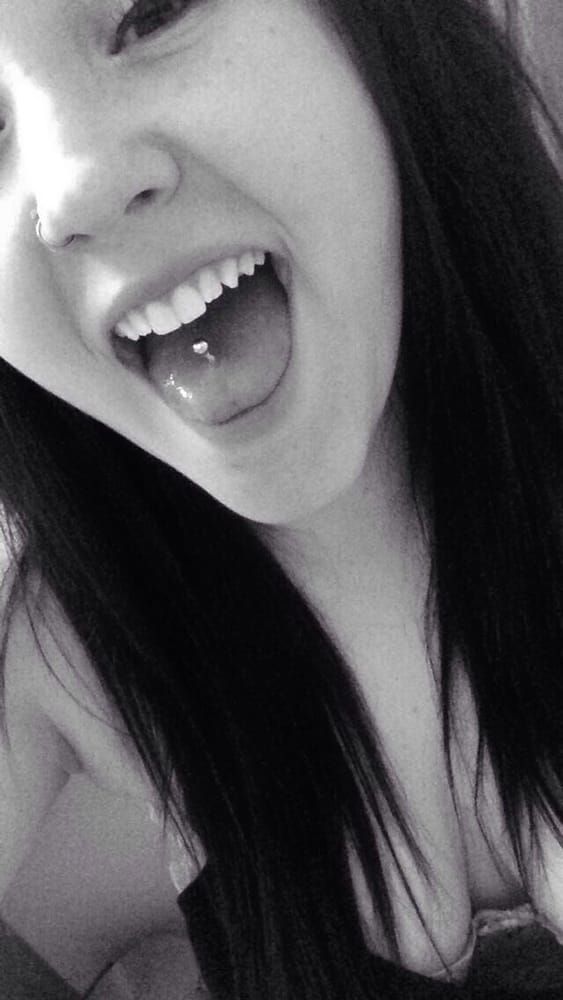 A black and white photo of a woman with her tongue out.