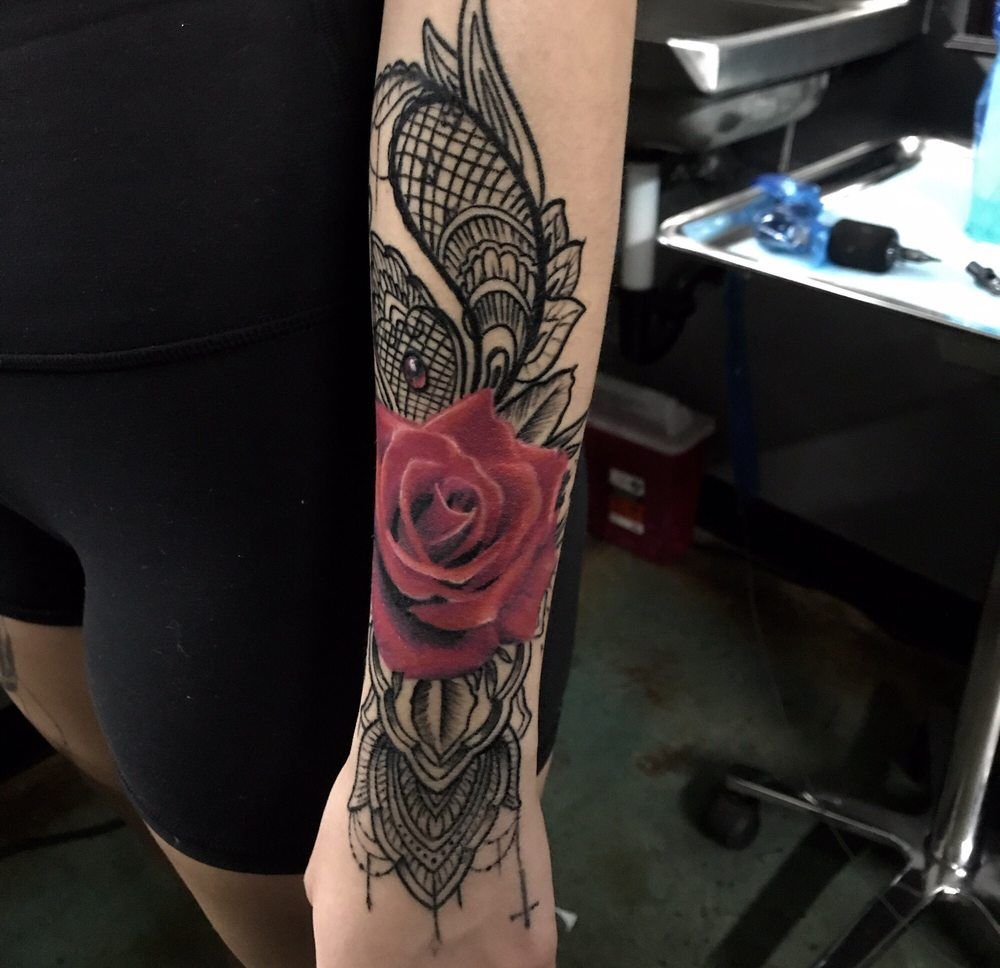 A woman has a tattoo of a red rose on her arm