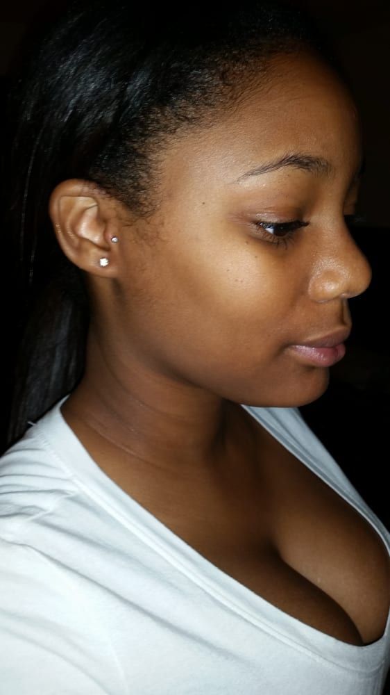A close up of a woman 's face wearing a white shirt and earrings.