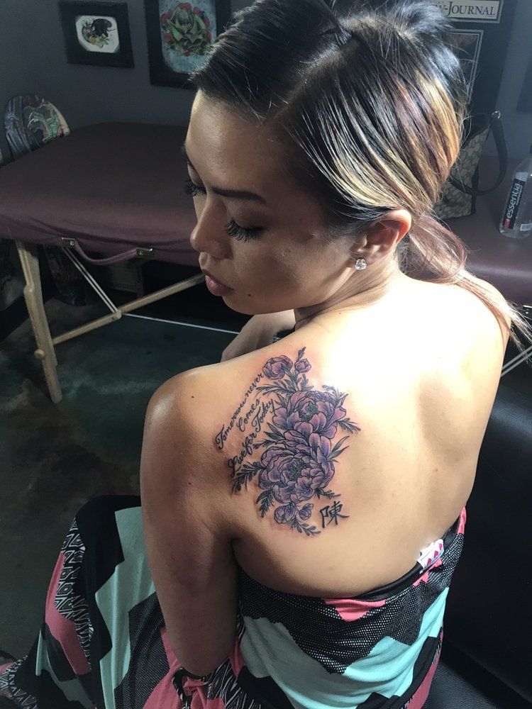 A woman with a tattoo on her back is sitting in front of a table.
