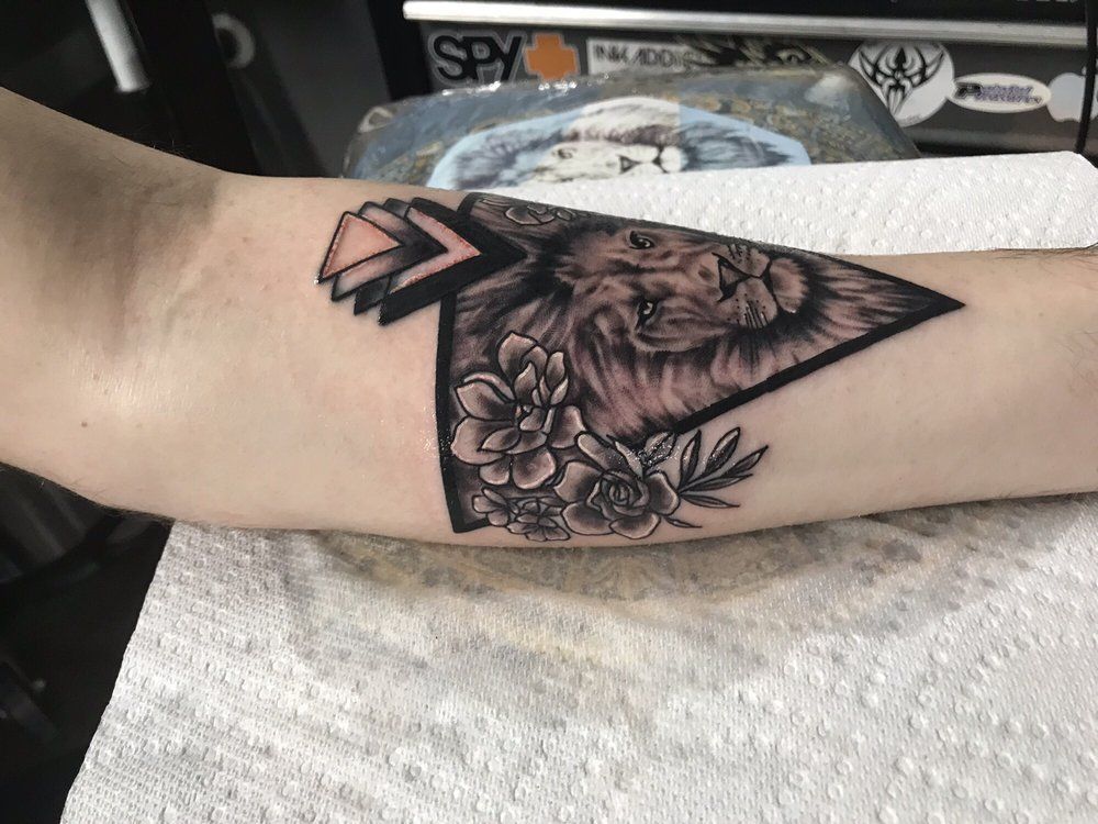 A tattoo of a lion and flowers on a person 's arm