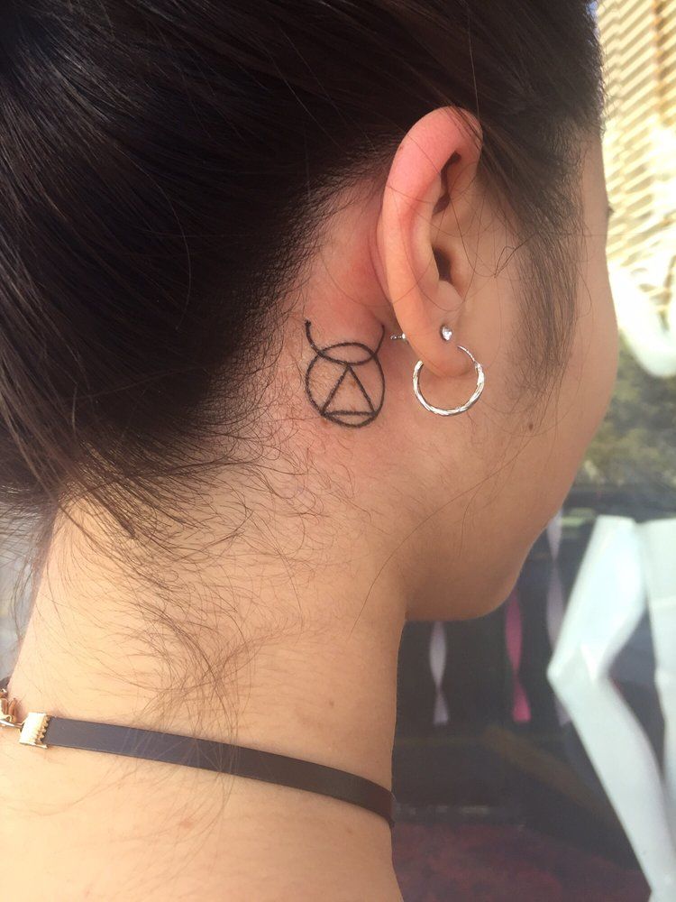 A woman has a tattoo on the back of her ear.