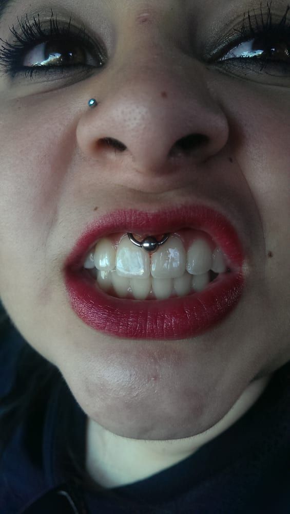 A close up of a woman 's mouth with red lips and a nose ring.