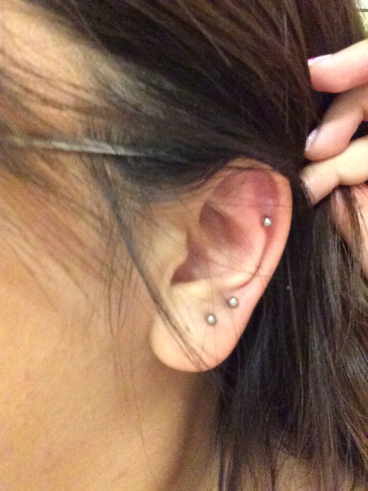 A close up of a woman 's ear with three piercings