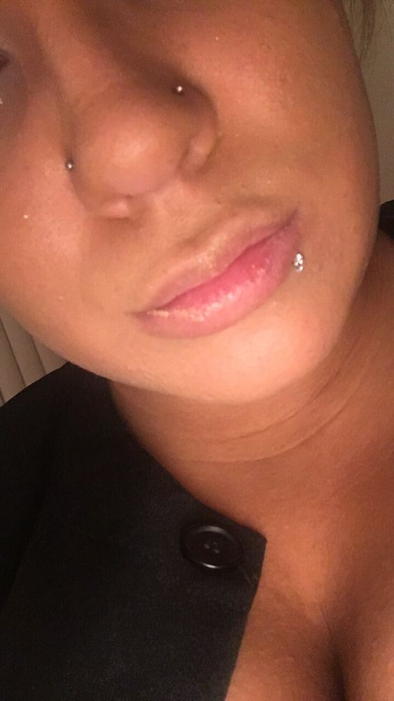 A close up of a woman 's face with a nose ring and lip piercing.