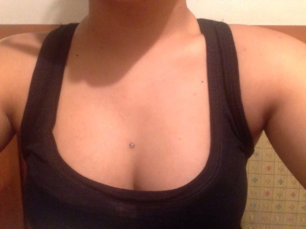 A woman in a black tank top has a piercing in her chest