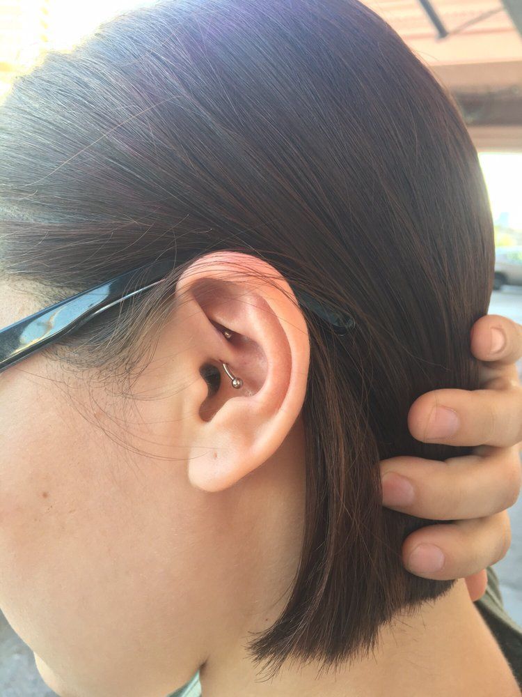 A close up of a woman 's ear with a piercing and glasses.