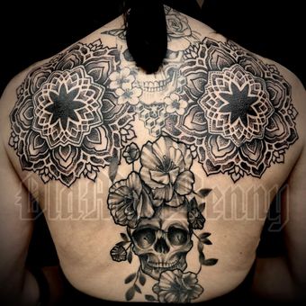 A woman has a skull and flowers tattoo on her back