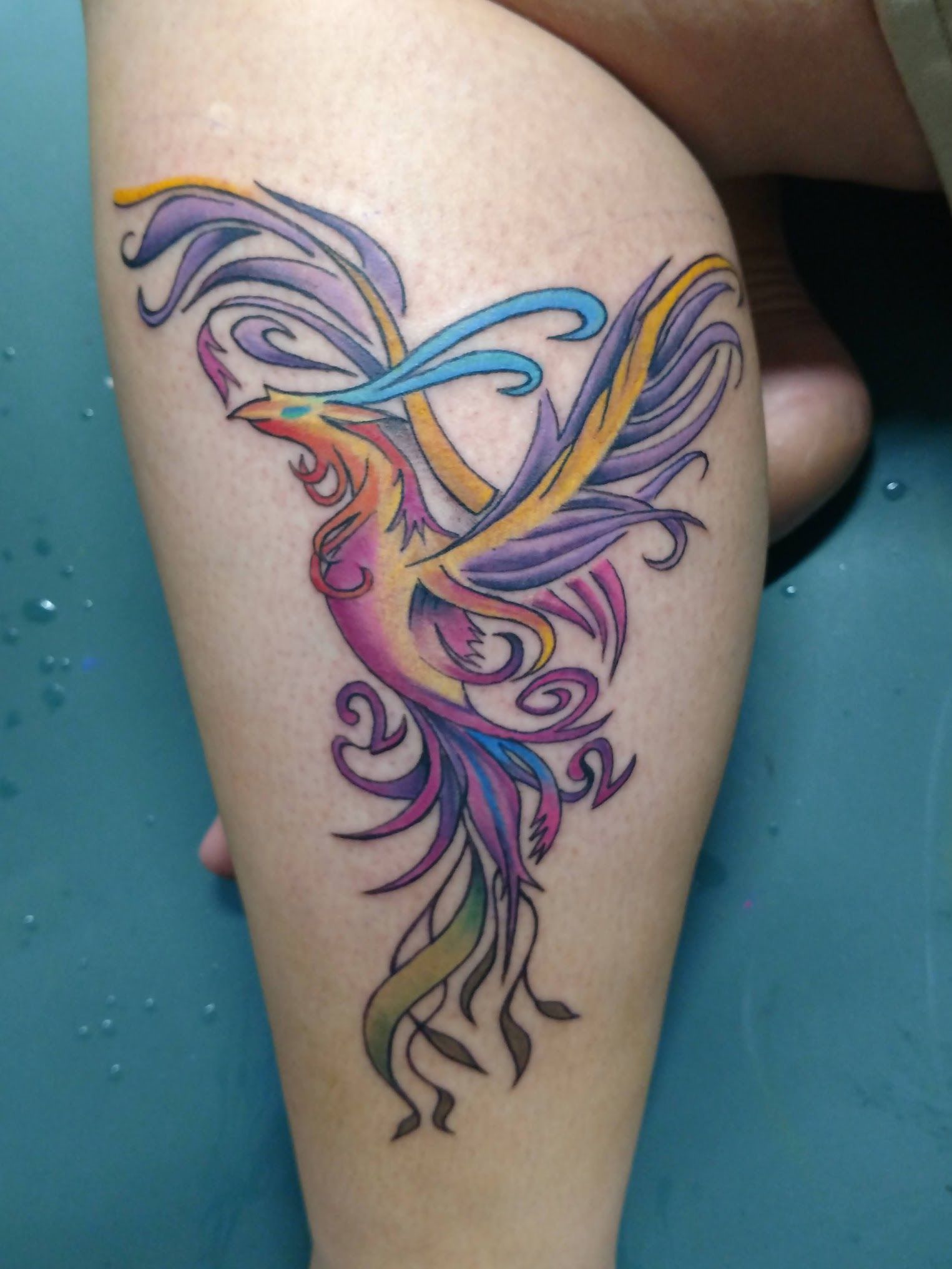 A woman has a colorful phoenix tattoo on her leg