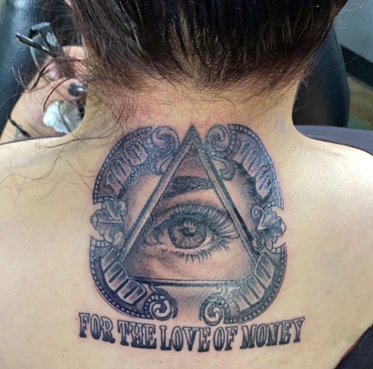 A woman has a tattoo on her back that says for the love of money