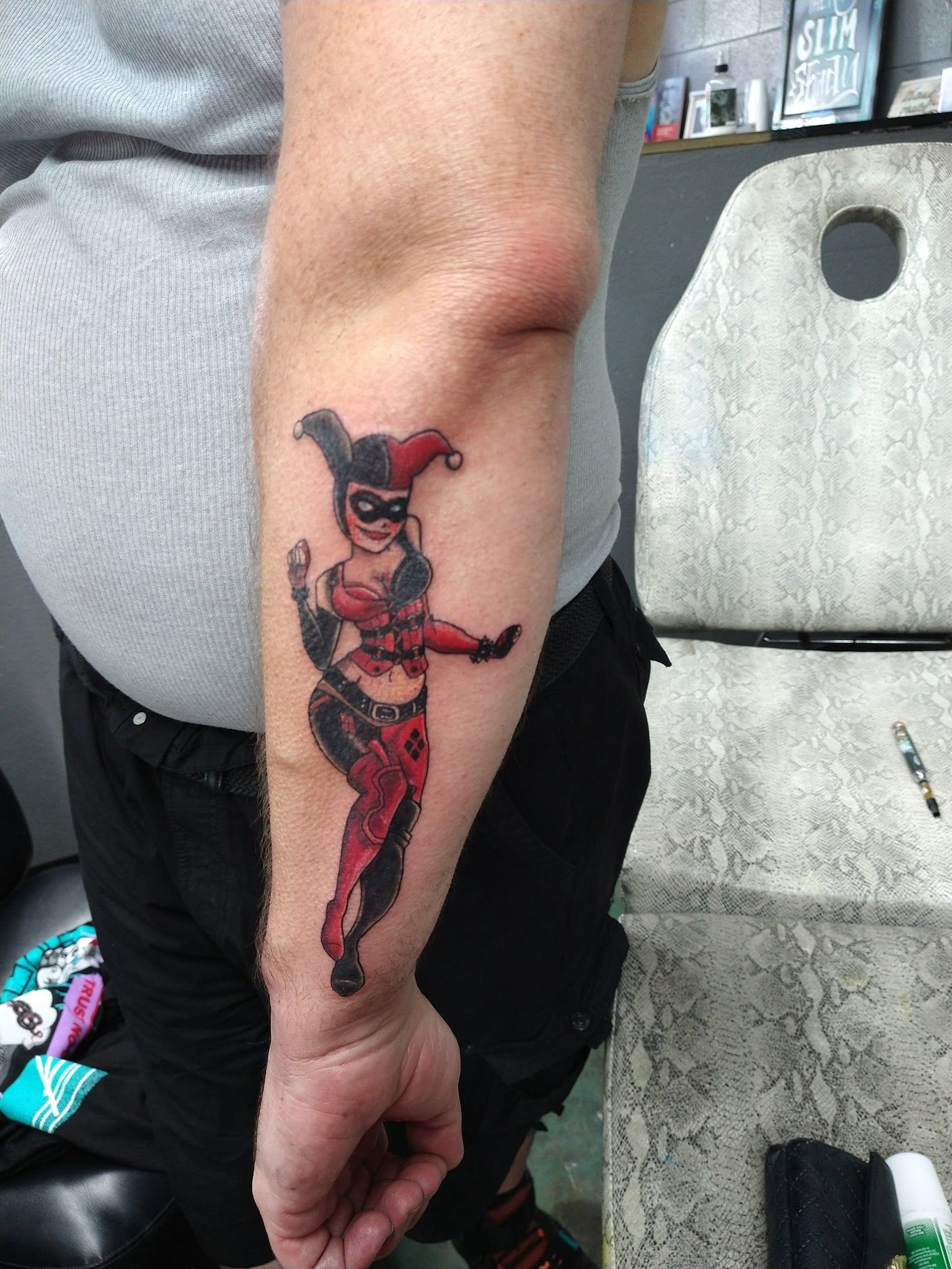 A man has a harley quinn tattoo on his forearm.