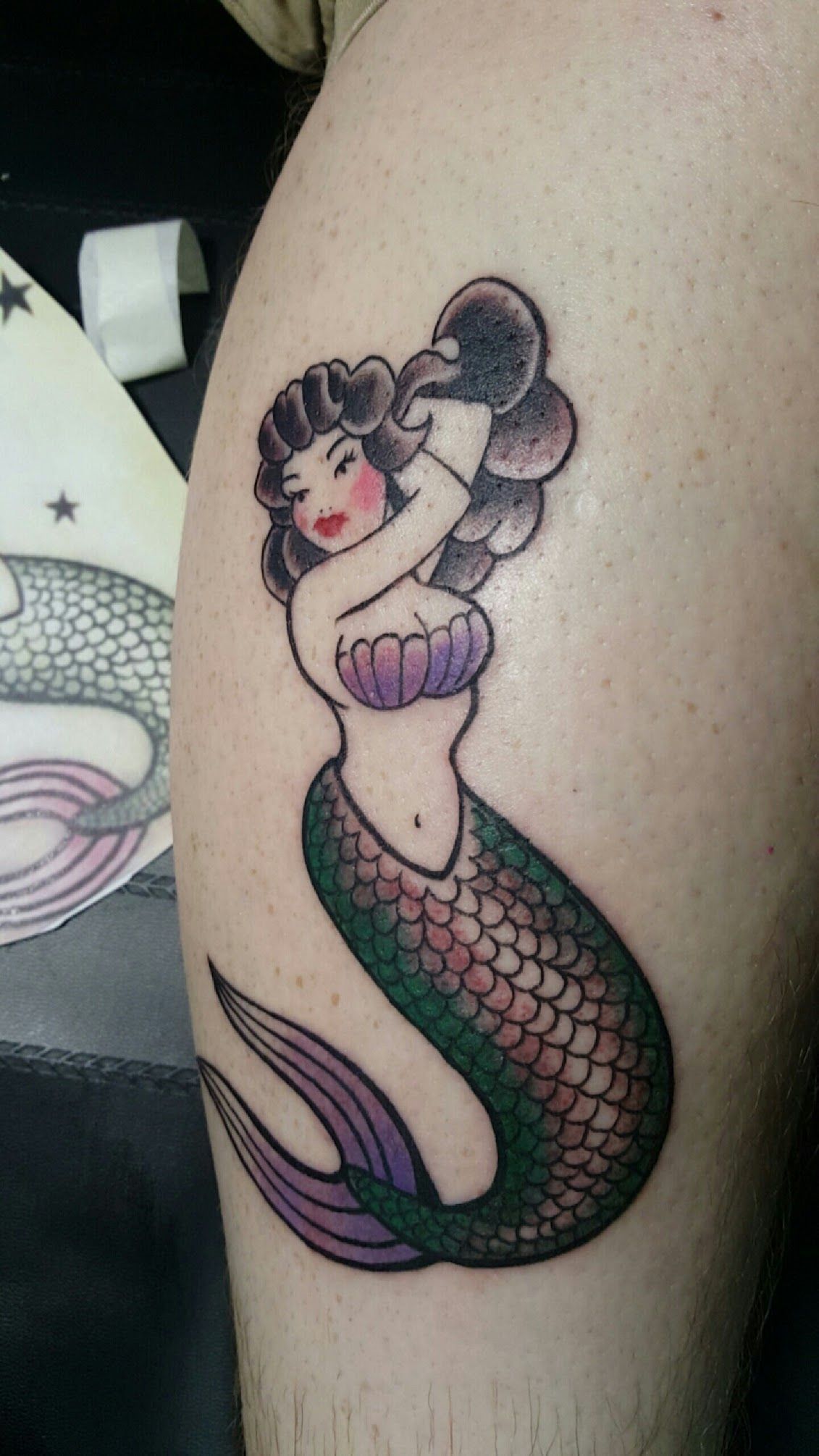 A tattoo of a mermaid on a person 's leg.
